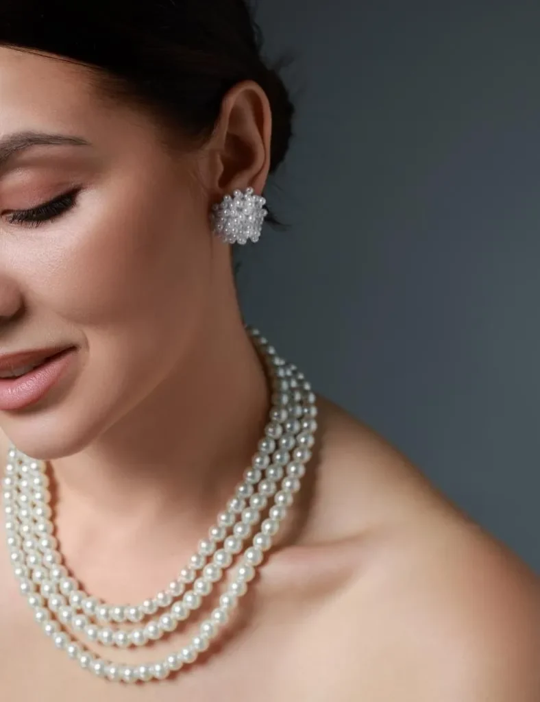 A girl wearing a pearl necklace and pearl studs.